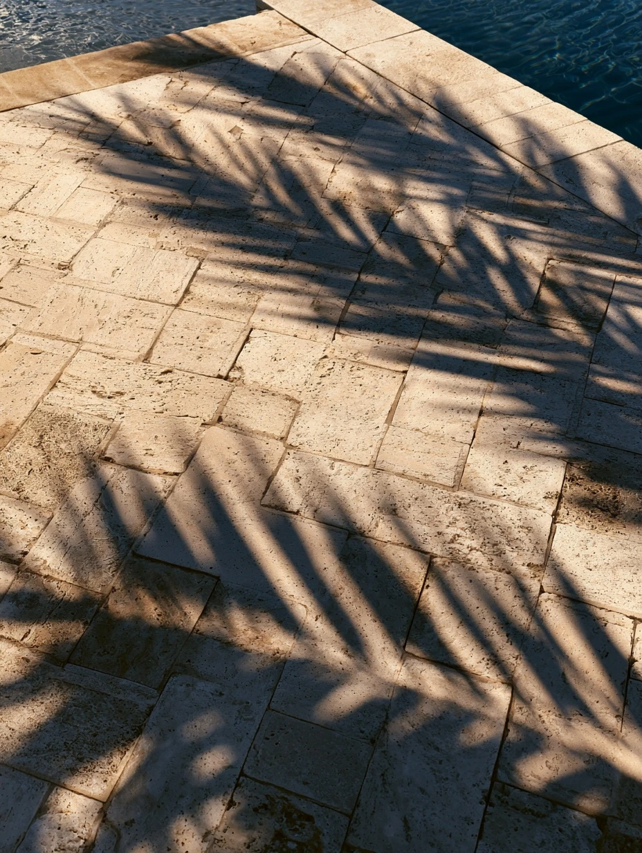 Travertine pool deck laid in a herringbone pattern beside blue water